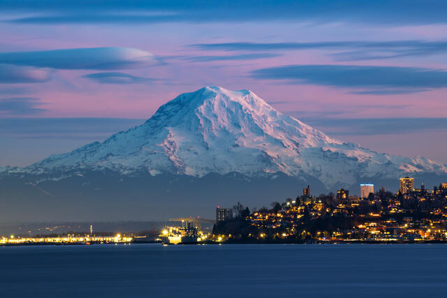 Mount Rainier glowing in alpenglow above Tacoma waterfront at dusk, viewed from Dune Peninsula along Ruston Way, Washington