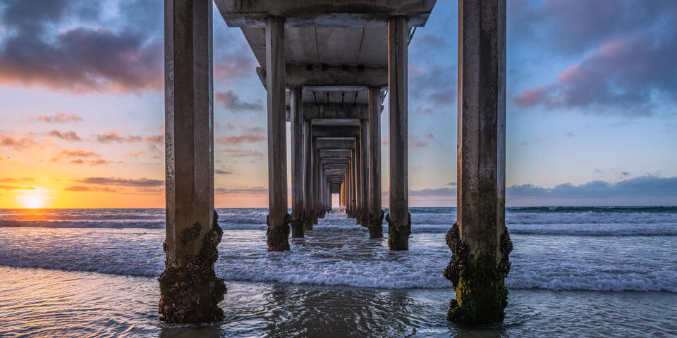 Fine art coastal photograph of Scripps Pier at sunset in La Jolla, California, featuring golden light reflecting on the Pacific Ocean and the iconic pier, captu